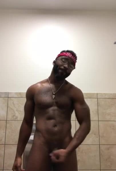 Muscular black guy stroking his dick in the gym bathroom
