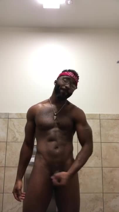 Muscular black guy stroking his dick in the gym bathroom